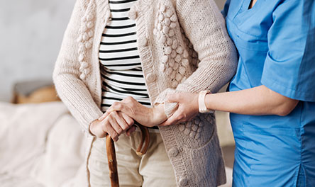 An older man with his hands on a cane with a nurse's hand on top. God can heal illness, depression, and thoughts of suicide.