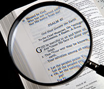 A stack of Bibles for research with a magnifying glass on top for full, detailed encyclopedia answers.